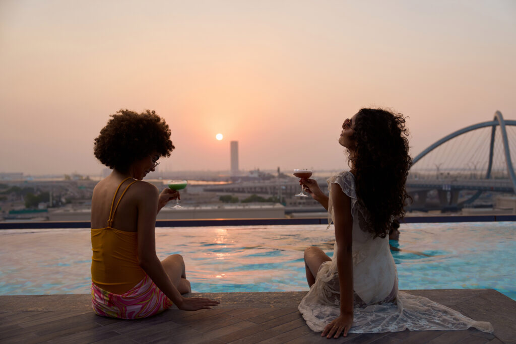 Two women enjoying sunset views at Ten64 Rooftop Pool Bar in Dubai's Deira district